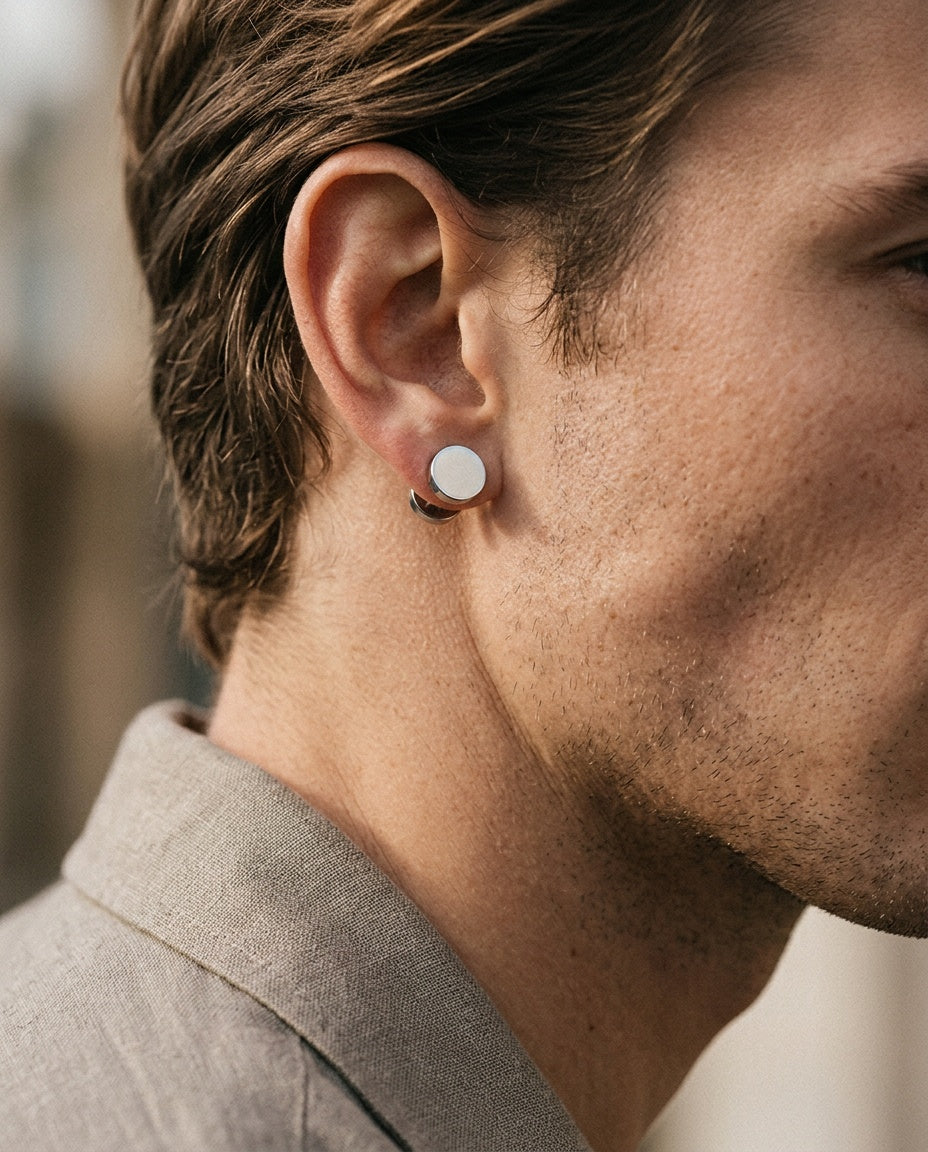 Flat silver disc stud worn on a man's earlobe