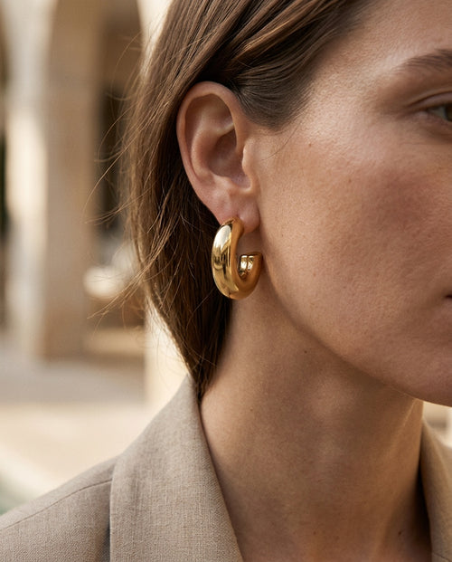 Thick gold hoop earring worn with hair pulled back