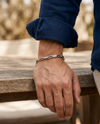 Paperclip chain bracelet worn on a man's wrist next to a watch