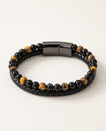 Tiger eye bracelet with yellow tiger eye and black beads next to braided leather