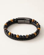 Tiger eye bracelet with yellow tiger eye and black beads next to braided leather