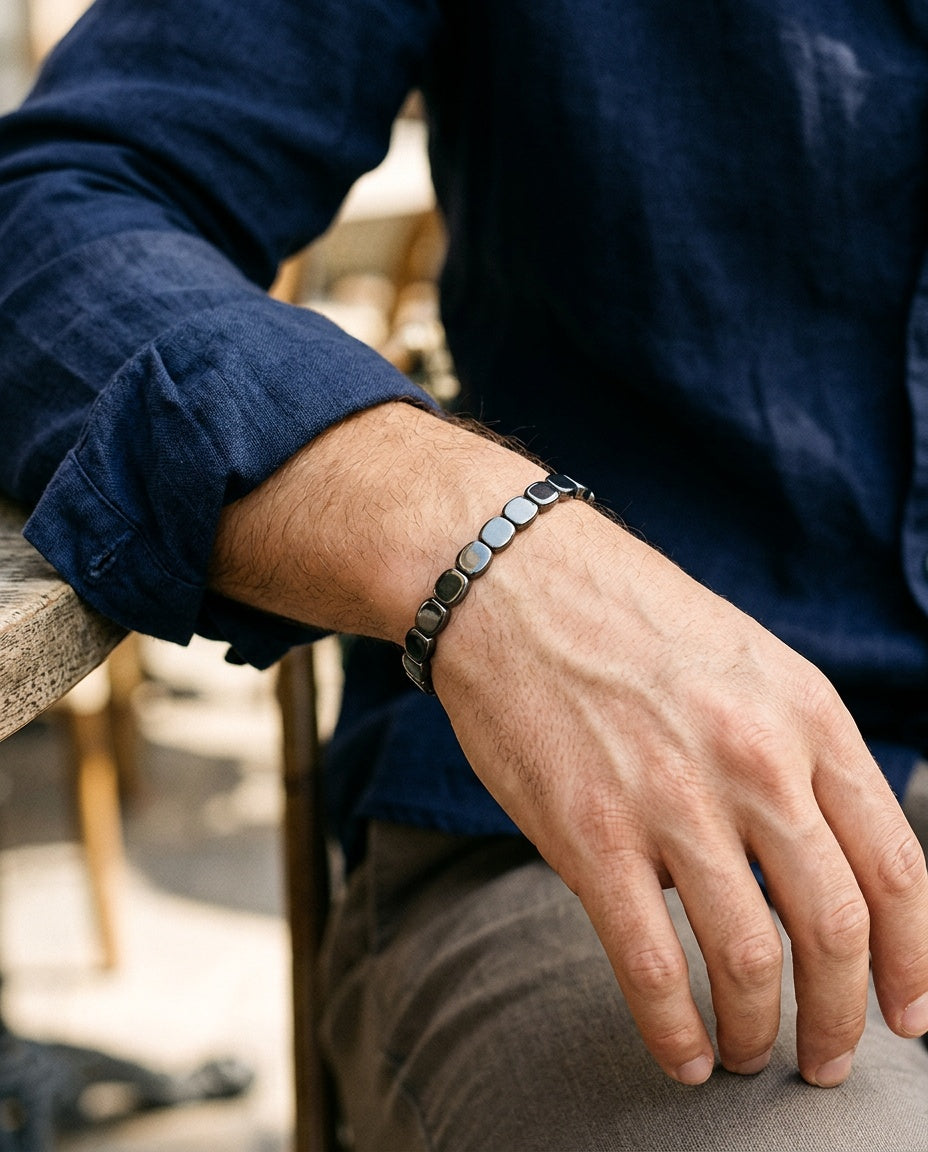 Bracelet hématite porté au poignet d'un homme, à côté d'une montre