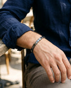 Bracelet hématite porté au poignet d'un homme, à côté d'une montre