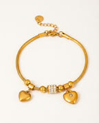 Heart bracelet in gold with heart charms and zircon details on a white background