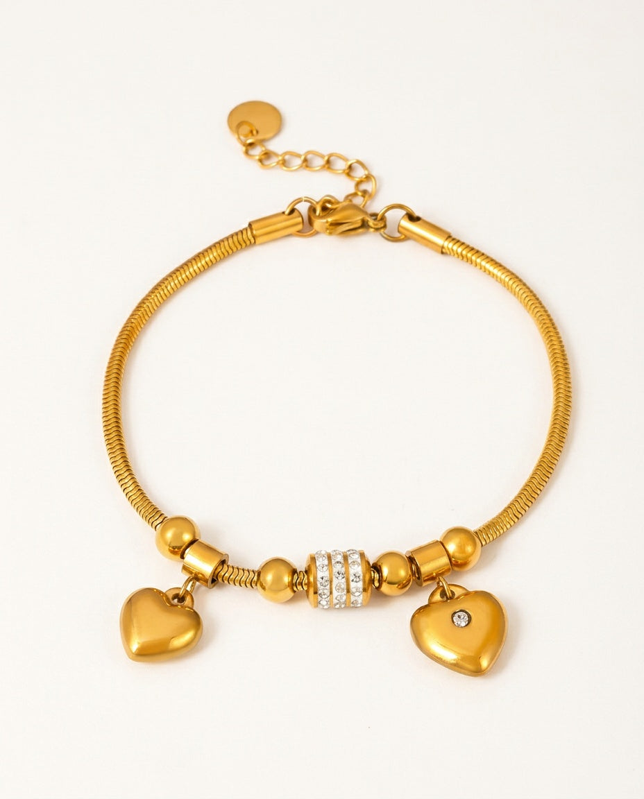 Heart bracelet in gold with heart charms and zircon details on a white background